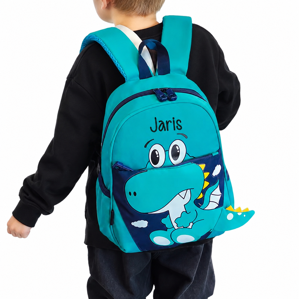 Personalisierbarer Kindergarten-Rucksack mit Dino-Design und Name Jaris, getragen von einem blonden Jungen im schwarzen Pullover