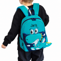 Personalisierbarer Kindergarten-Rucksack mit Dino-Design und Name Jaris, getragen von einem blonden Jungen im schwarzen Pullover